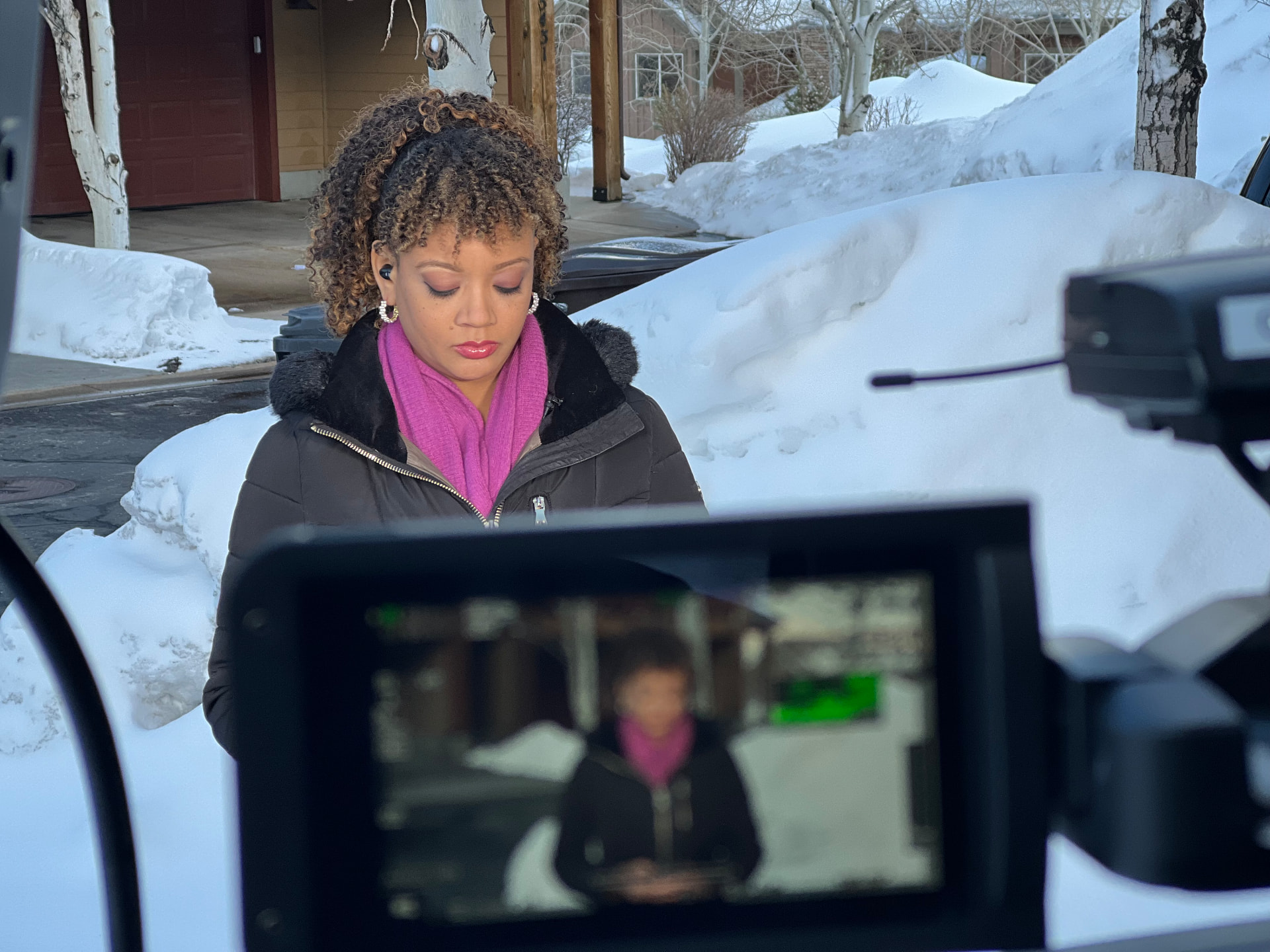 A field correspondent framed on a production monitor during a winter assignment
