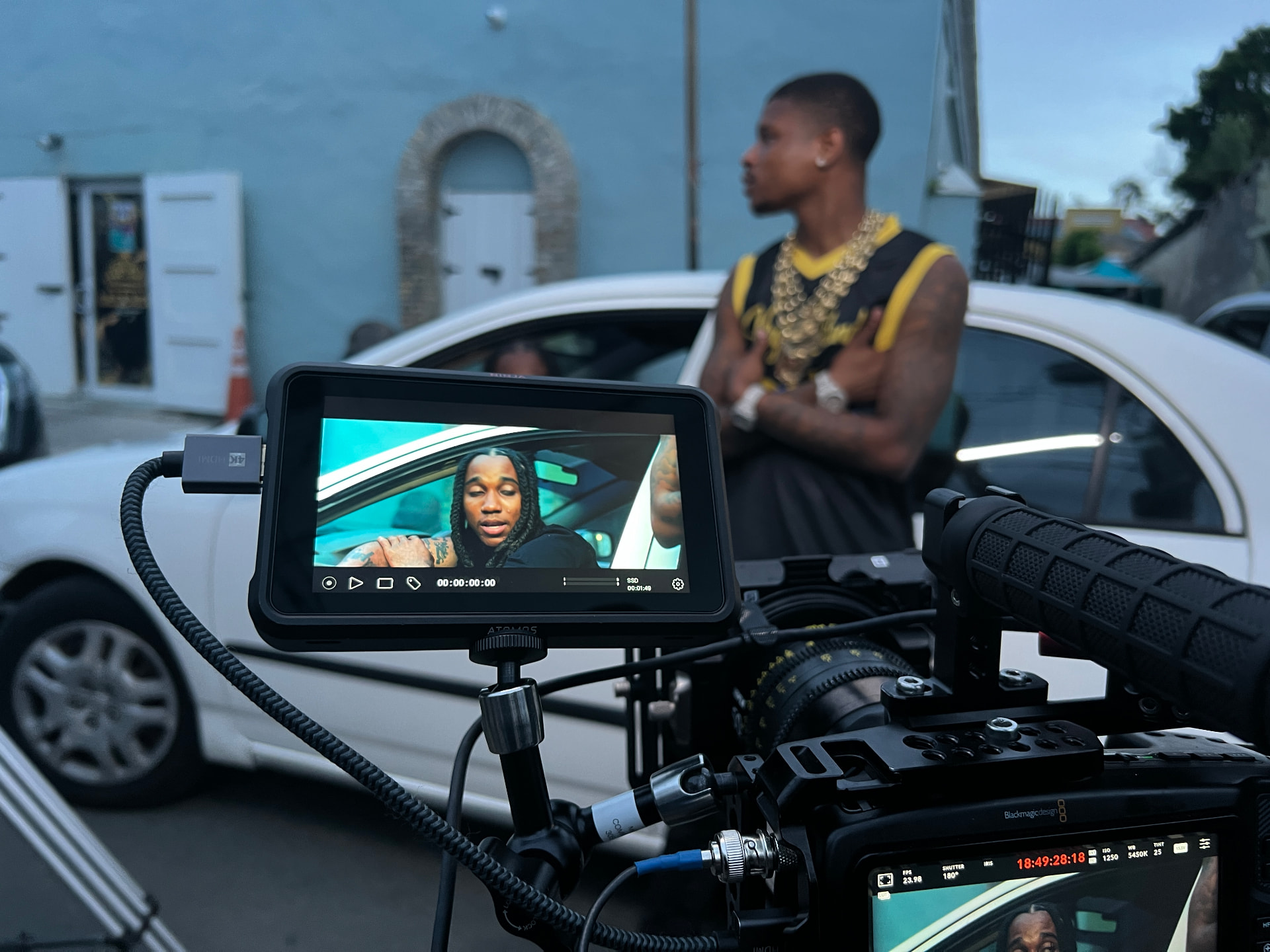A cinema camera and production monitor framing talent on a street set