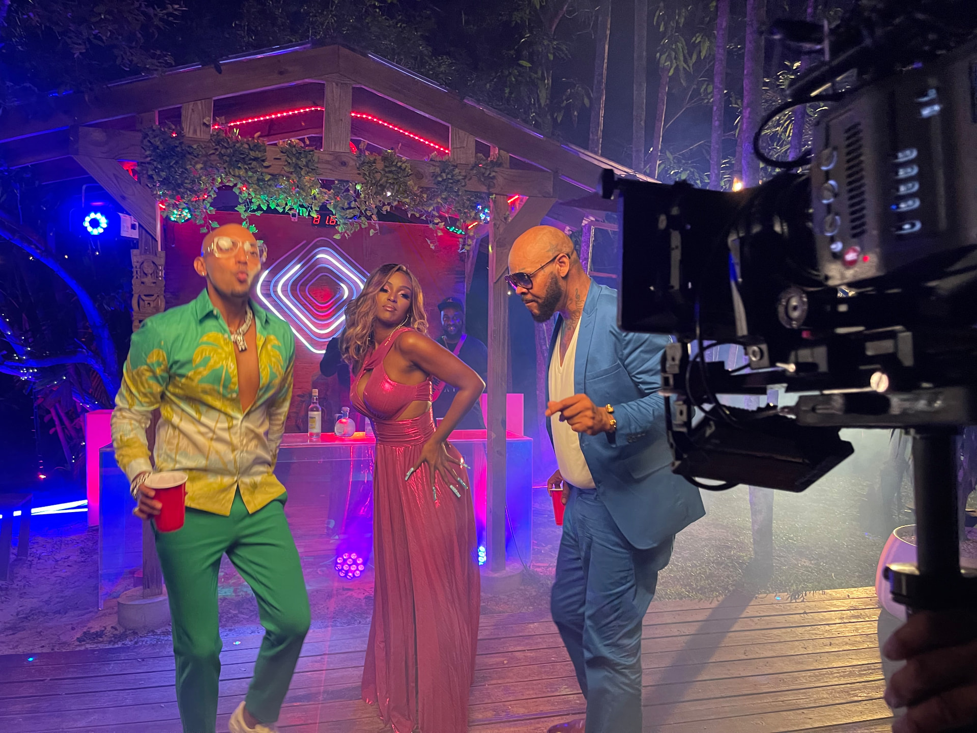 A professional cinema camera filming performers on a colorful outdoor night set